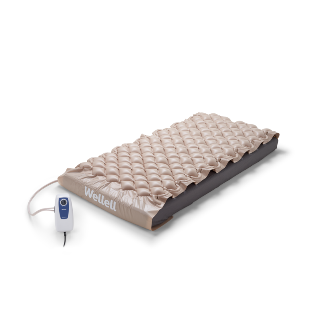 The Wellell Domus 1 Alternating Pressure Mattress is a beige bubble-style mattress connected to a compact white and blue electric pump controller, designed for effective pressure ulcer prevention.